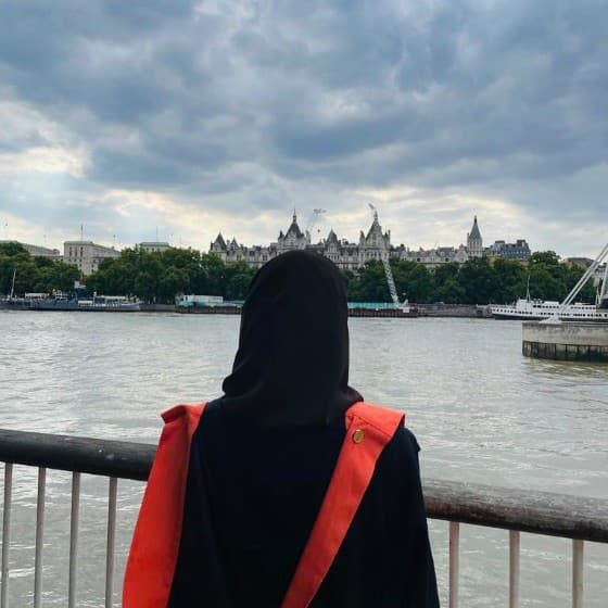 MK Dietitian in graduation attire overlooking the Thames in London